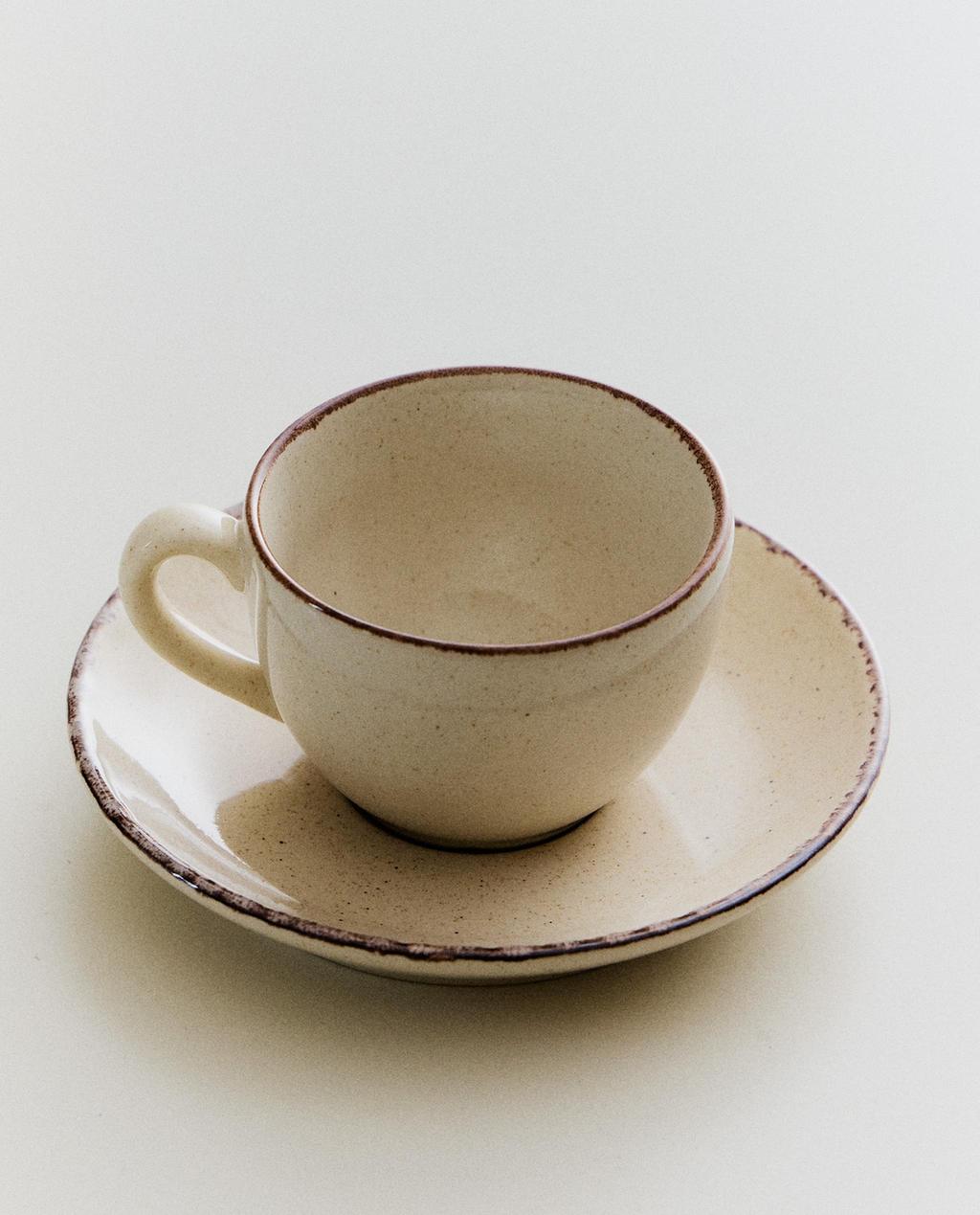 STONEWARE TEACUP AND SAUCER WITH ANTIQUE FINISH RIM