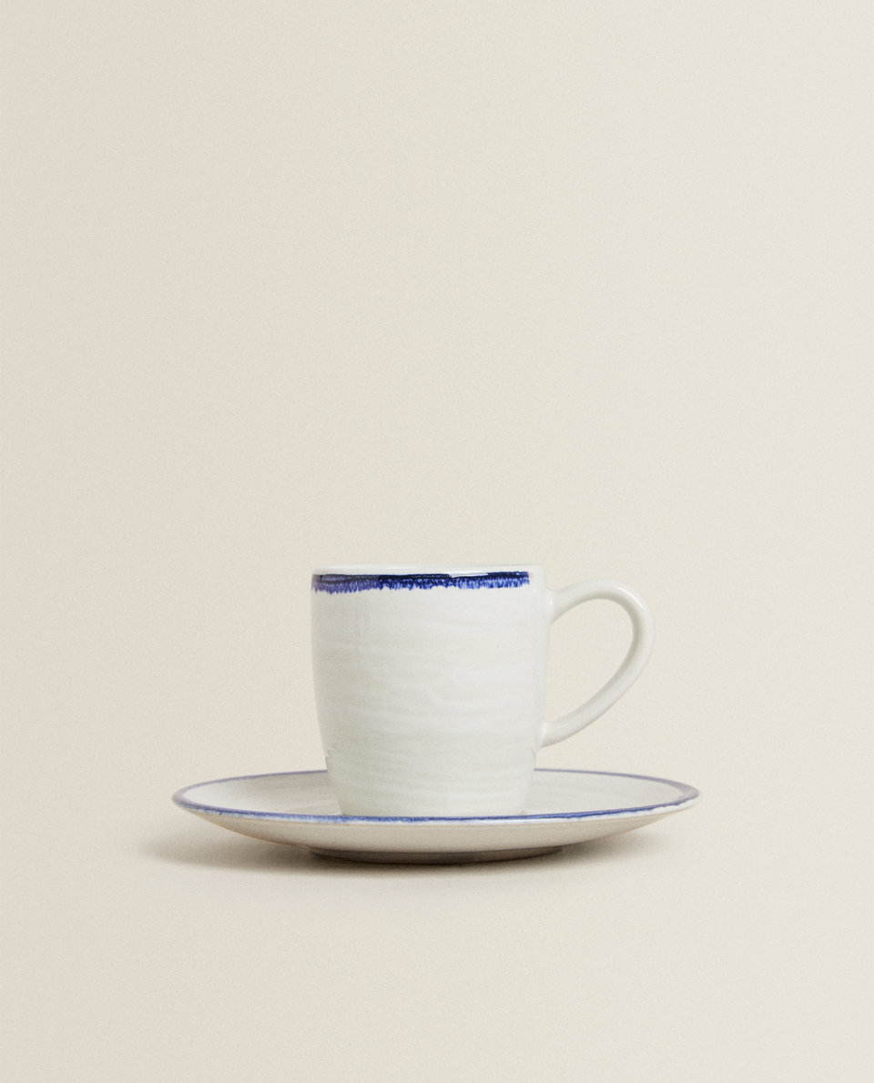 فنجان قهوة مع طبق من الخزف الحجري بتصميم بارز وحافة زرقاء