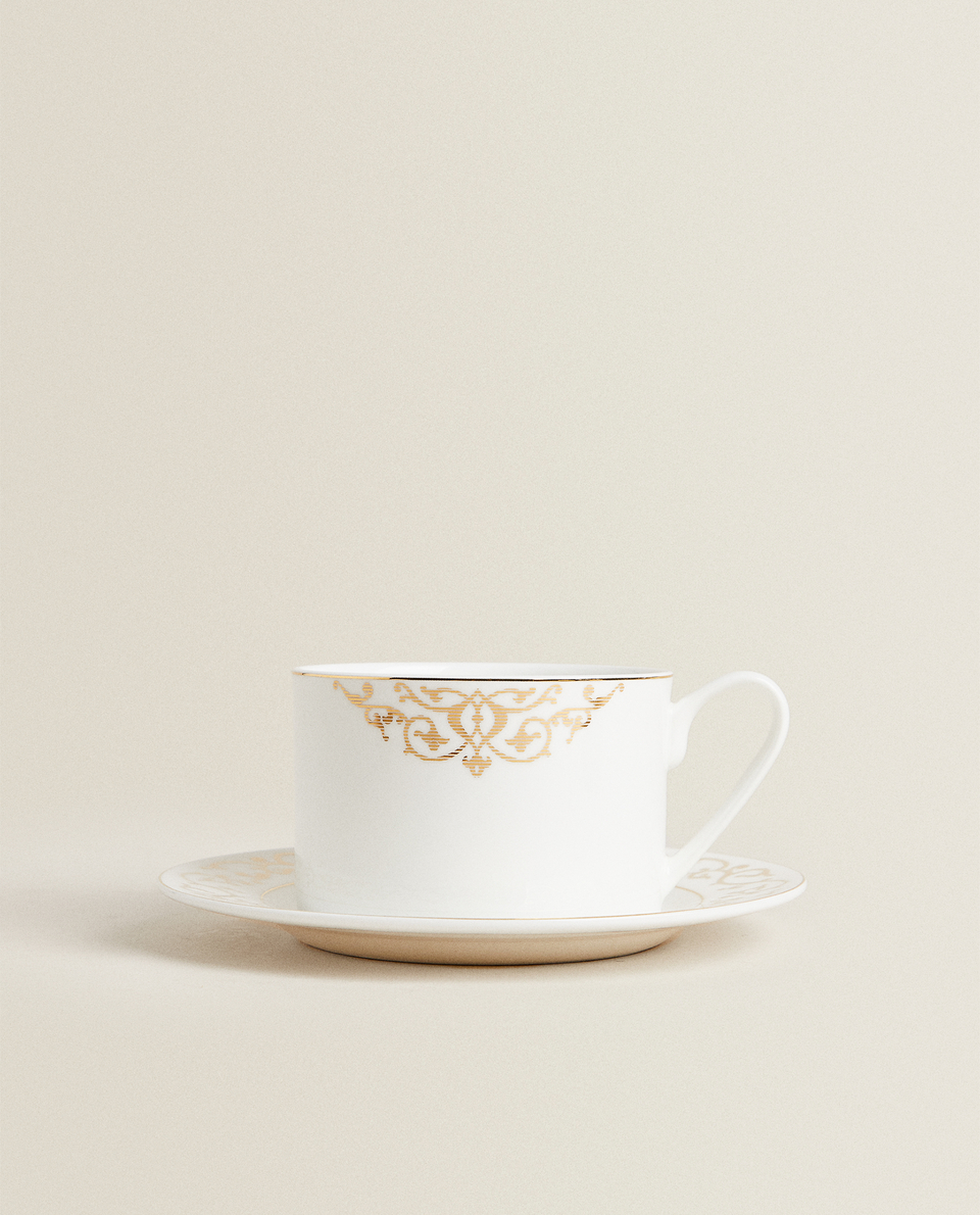 فنجان شاي وطبق من خزف رماد العظام بحافة ذهبية