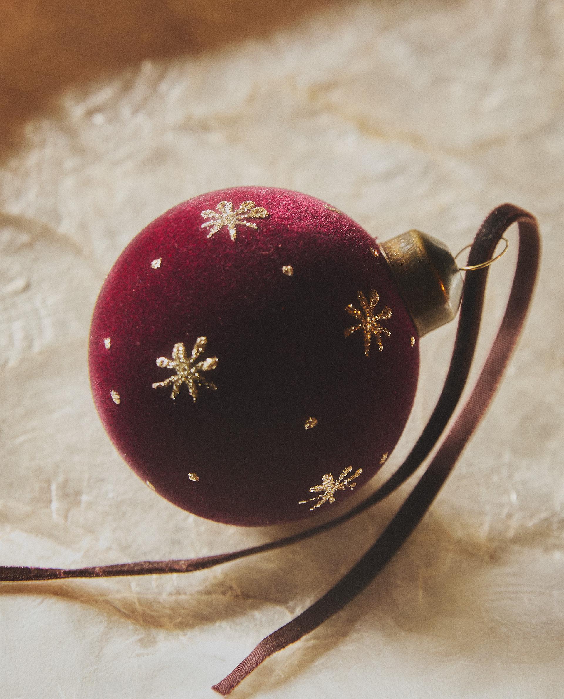 Božična krogla v granatni barvi z žametnim zaključkom in potiskom zlatih zvezd, z vrvico za obešanje.