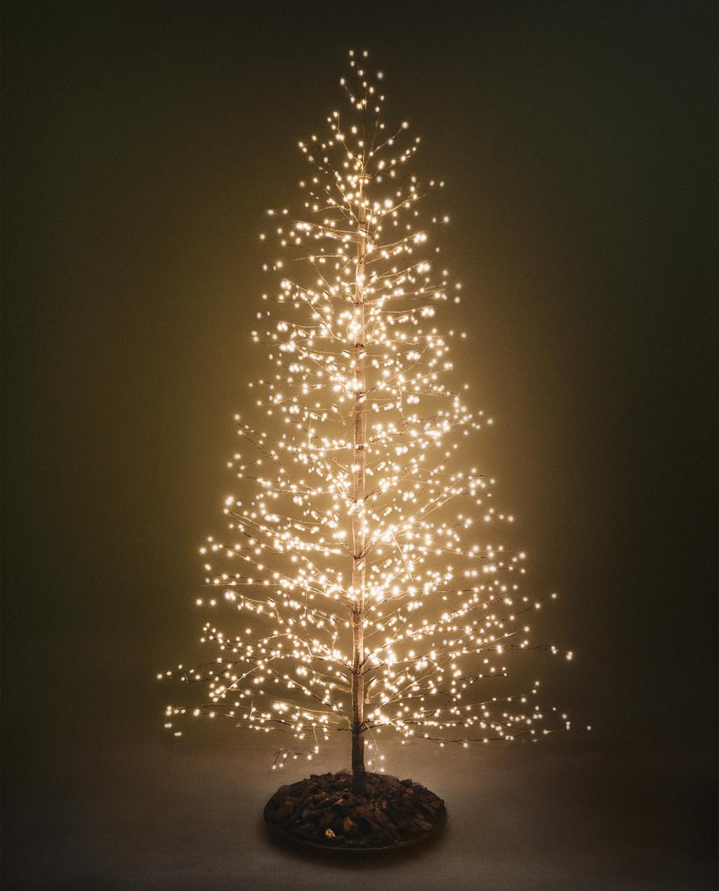 Božično drevo rjave barve z LED lučkami na vejah, okrasno okroglo podnožje.