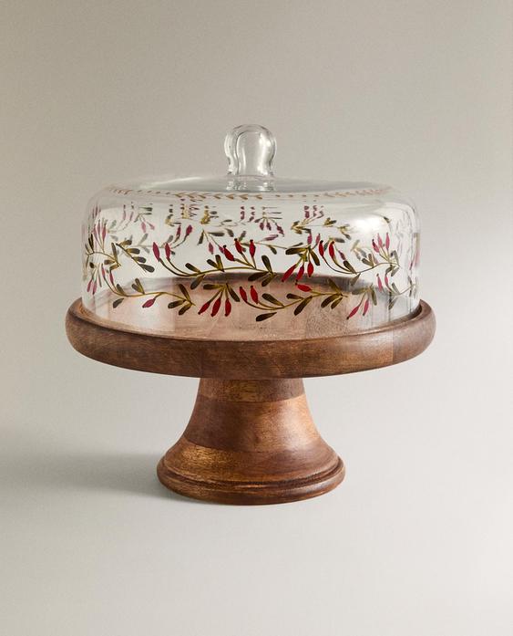 Krožnik za torte z lesenim podstavkom in stekleno kupolo, poslikano z rdečimi in zelenimi motivi.